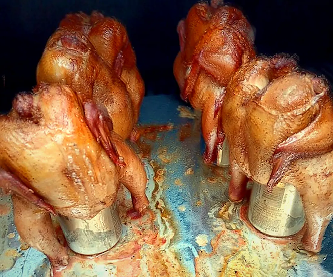 Whole chickens standing upright in the smoker, golden from the smoke